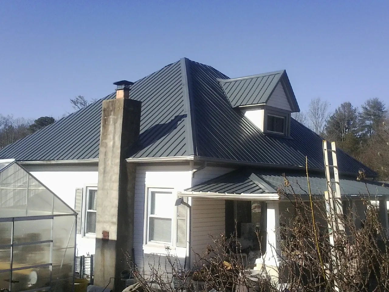Dark blue standing seam metal roof on a white farmhouse with dormer — Slate & Tile Roof Repair by Roofing Brothers in Garwood