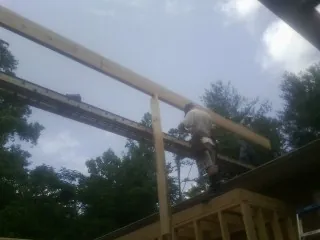 Carpenter setting a ridge beam over a new addition frame — Ice Dam Removal by Roofing Brothers in Garwood