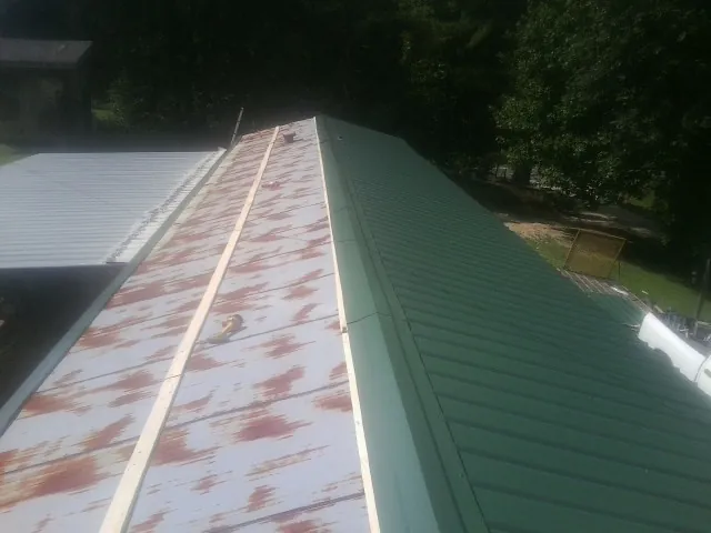 Old rusted panels beside newly installed green metal roofing — Wind Damage Roof Repair by Roofing Brothers in Garwood