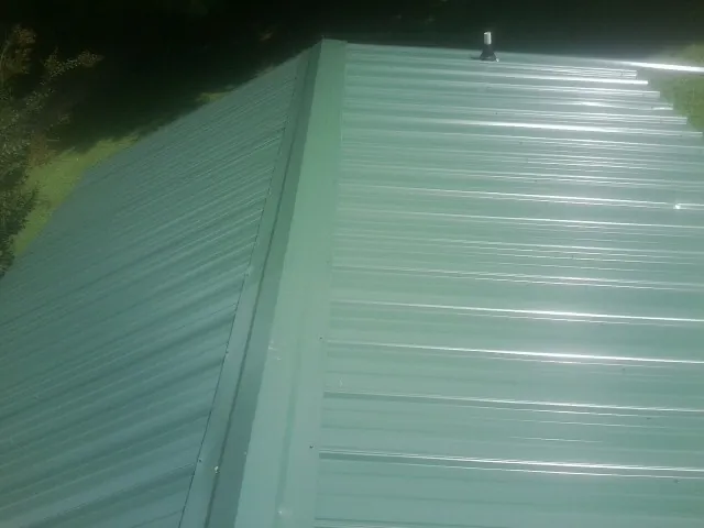 New green metal panels meeting at the ridge of a roof — Flat Roof Repair work by our crew in Garwood