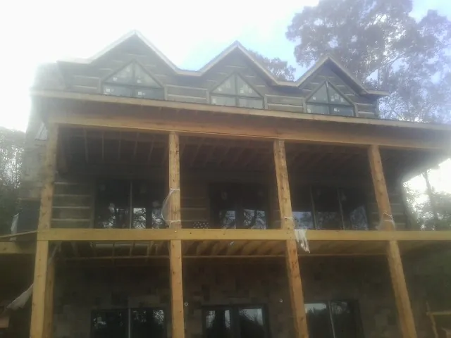 Dormers and porch framing on a large log home under construction — Roof Coating work by our crew in Garwood