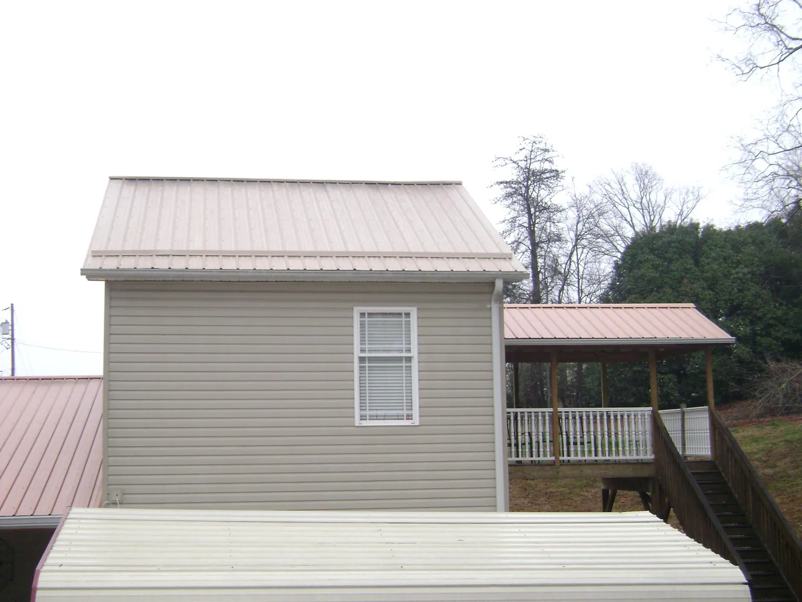 Tan metal roofs on a two story addition and attached porch, from a Roof Replacement job in Garwood